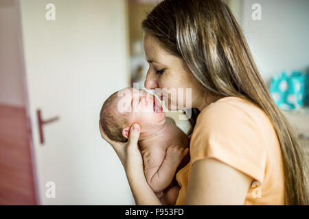 Newborn baby crying in mother hands indoor Stock Photo