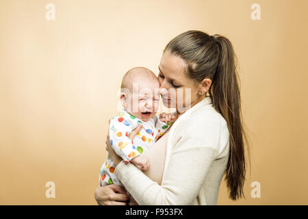 Crying child with mother studio shot on beige background Stock Photo