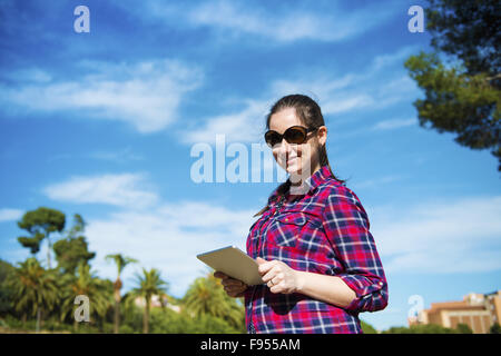 Pretty young female tourist using digital tablet, portrait with blue sky Stock Photo