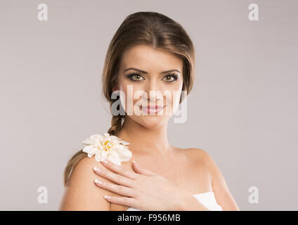 Portrait of beautiful woman with white flower in her hair. Isolate on grey background. Stock Photo