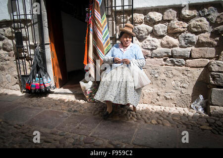 Cusco , Peru. A woman sits in the sun on a small side street . Stock Photo