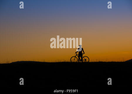 Silhouette of mountain biker in sunset on the meadow Stock Photo