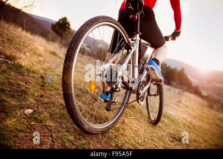 Detail of cyclist man feet riding mountain bike on outdoor trail in sunny meadow Stock Photo