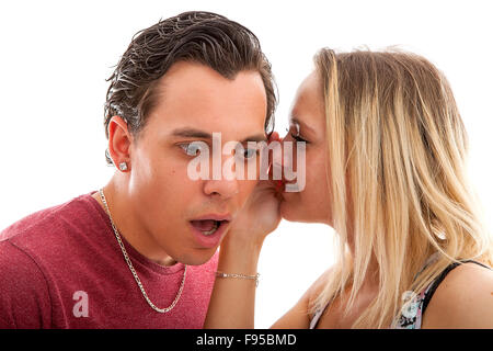 girl is whispering in ear of boyfriend isolated on white background nad he is startled Stock Photo