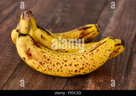 closeup of a bunch of ripe bananas on a wooden surface Stock Photo