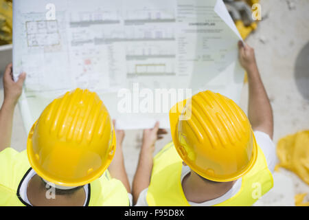 Engineer builders in safety vest with blueprint at construction site Stock Photo