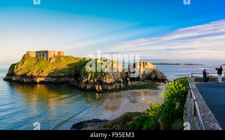 A man take a photograph of a woman with St Catherine's Island as a background, Tenby, Pembrokeshire, west Wales, UK Stock Photo
