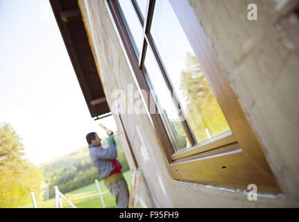 Man applying foam sealant with caulking gun to insulate the window Stock Photo