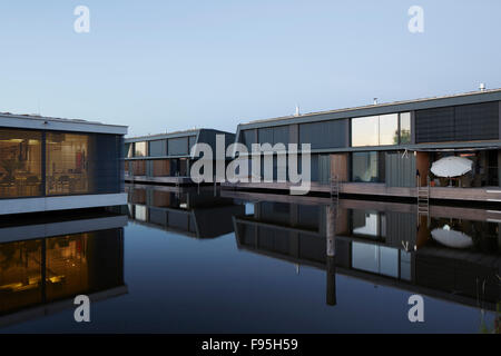Housing development at Lake Neusiedl, Neusiedl am See, Burgenland, Austria. Exterior view showing a reflection in calm water at the contemporary lakeside development of fully-glazed houses at Neusiedl am See, Burgenland, Austria. Stock Photo