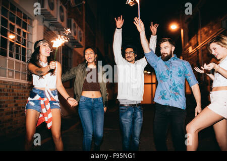 Portrait of happy young friends celebrating new years eve with sparklers at night. Best friends hanging out at night and celebra Stock Photo
