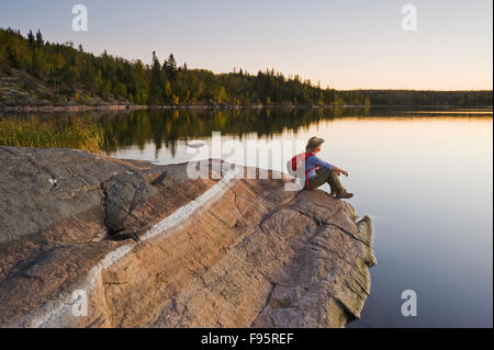 hiker on rock, Devil Lake,  Northern Saskatchewan, Canada Stock Photo
