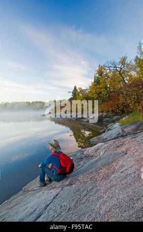 hiker on Canadian Shield rock, Namau Lake, Whiteshell Provincial Park, Manitoba, Canada Stock Photo