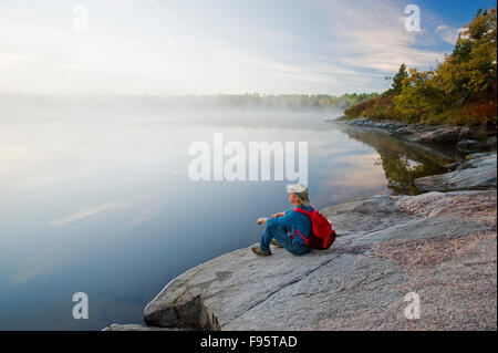 hiker on Canadian Shield rock, Namau Lake, Whiteshell Provincial Park, Manitoba, Canada Stock Photo