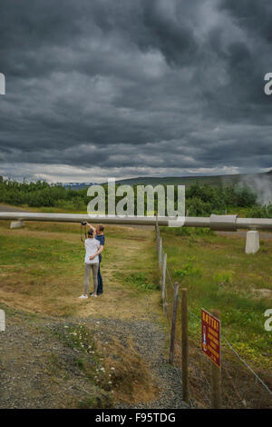 Couple taking a selfie kissing by hot water pipes at Deildartunguhver Hot Spring, Reykholtsdalur, Iceland Stock Photo