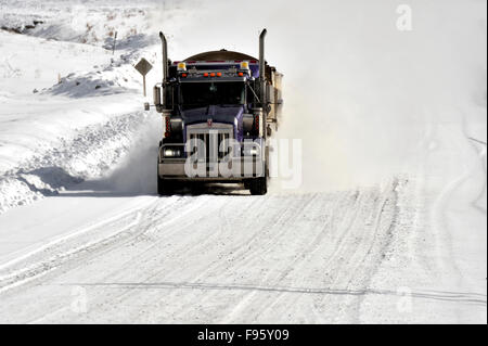 A tractor trailer traveling on a snow covered road in rural Alberta Canada Stock Photo