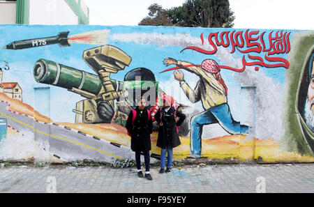 Rafah, Gaza Strip, Palestinian Territory. 14th Dec, 2015. Palestinian children walk past a wall painted with a mural during a rally marking the 28th anniversary of Hamas' founding, in Rafah southern Gaza strip December 14, 2015 Credit:  Abed Rahim Khatib/APA Images/ZUMA Wire/Alamy Live News Stock Photo