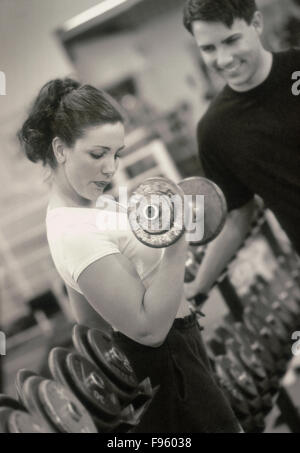 Caucasian female and male lifting weights in fitness club (Model Released) Stock Photo