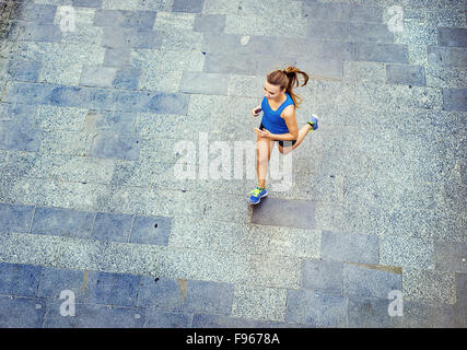 High angle view of young female runner jogging on tiled pavement old city on center. Stock Photo