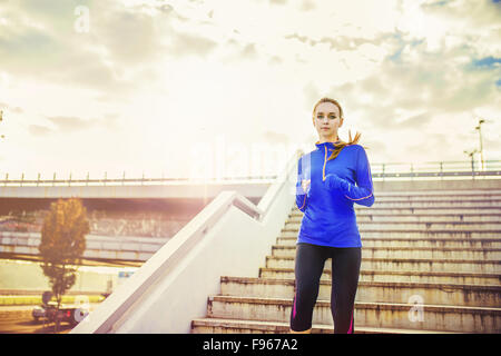 Female runner running down the stairs in city center Stock Photo