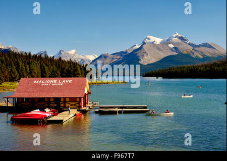 An image of Maligne Lake showing the boat house with people paddeling canoes in the rocky mountains in Jasper National Park Stock Photo