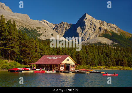 An image of Maligne Lake showing the boat house with people paddeling canoes in the rocky mountains in Jasper National Park Stock Photo