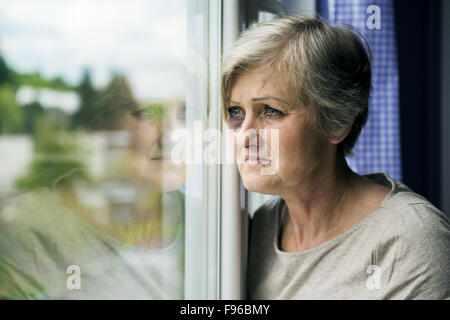 Scared woman is looking through the window. Having bruise on her face Stock Photo