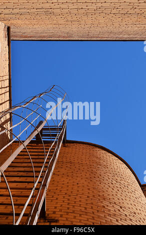 Industrial ladder, blue sky and brick walls of the building, bottom view. Stock Photo