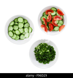 Fresh tomatoes, cucumbers and green onions chopped in salad. Three plates of salad isolated on a white background. Stock Photo
