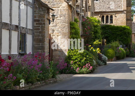 Colourful summer flowers and fine stone houses line a quiet street in the Cotswolds village of Stanton, Gloucestershire, England Stock Photo