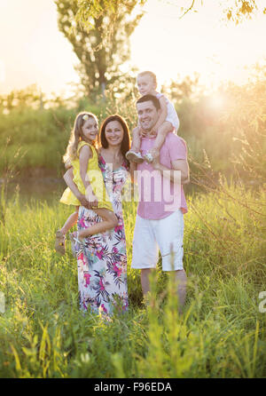 Portrait of young happy family in sunny meadow Stock Photo