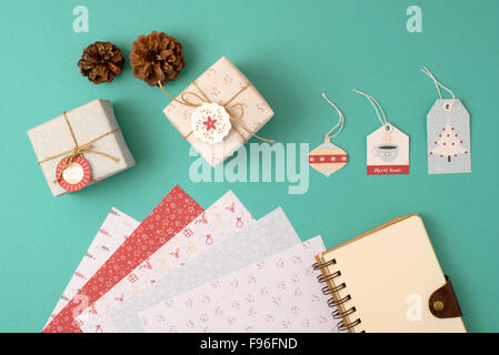 Christmas stationery arrangement top view elements template. Empty spiral notebook with wrapping paper stack, vintage gift boxes Stock Photo