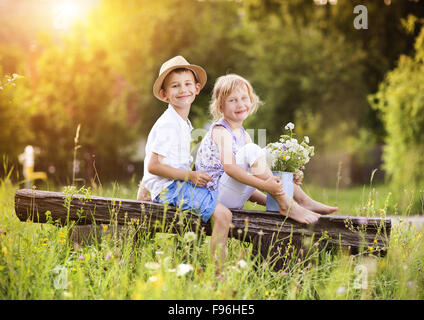 Cute boy and girl in love. They sitting on bench at sunset. Stock Photo