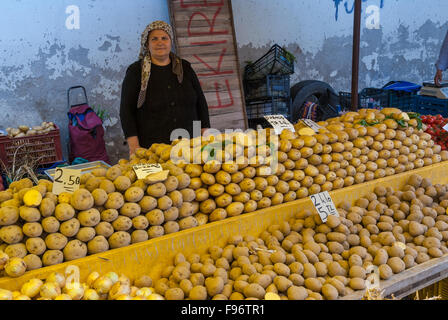 A woman with traditional clothes sells potatoes in the open market of the city on April 24, 2014 in Ayvalik, Turkey. Stock Photo