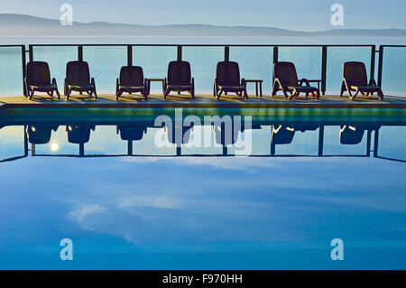 A horizontal image of  a line of chairs at an outdoor swimming pool at vacation resort on Vancouver Island B.C. Canada. Stock Photo