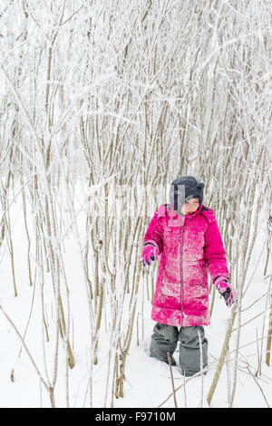 Young Girl Walking Through Snowy Winter Forest WIth Pink Coat Stock Photo