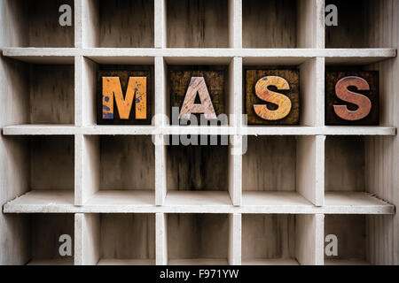 The word 'MASS' written in vintage ink stained wooden letterpress type in a partitioned printer's drawer. Stock Photo