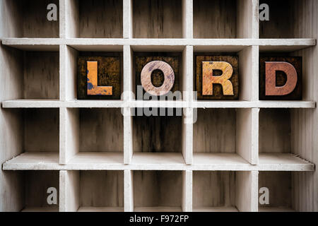 The word 'LORD' written in vintage ink stained wooden letterpress type in a partitioned printer's drawer. Stock Photo