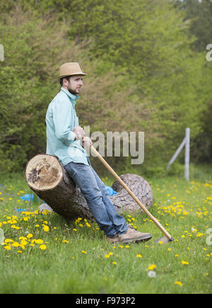 Young handsome man is having break during his working with hoe in backyard garden Stock Photo