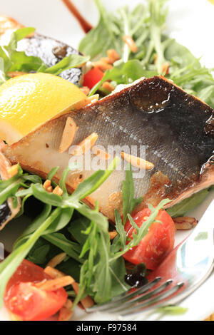 Fish fillets on bed of salad greens sprinkled with chopped almonds Stock Photo