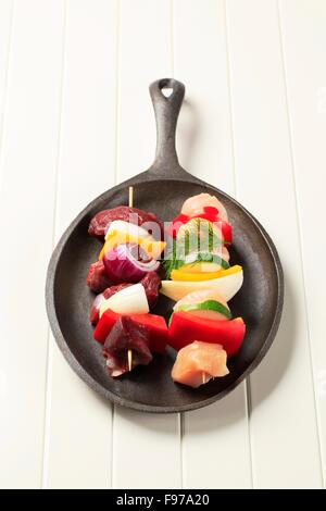 Raw shish kebabs on cast iron pan Stock Photo