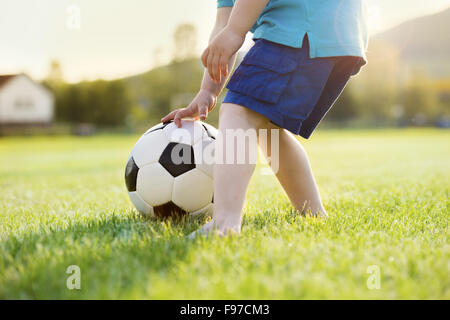 Close-up of little boy playing football on football pitch Stock Photo