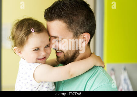 Indoor portrait of young father hugging his little daughter Stock Photo