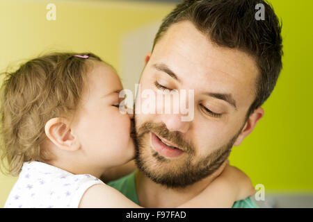 Indoor portrait of young father hugging his little daughter Stock Photo