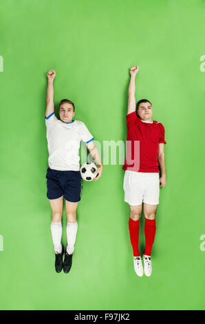 Two football players in a superman pose. Studio shot on a green backroung. Stock Photo