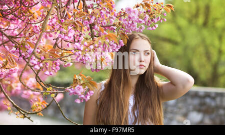 Beautiful girl in spring garden among the blooming trees with pink flowers Stock Photo