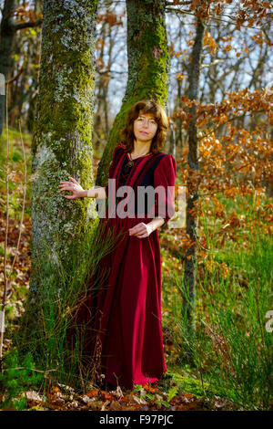 Woman in red renaissance dress portrait, autumnal forest, France Stock Photo