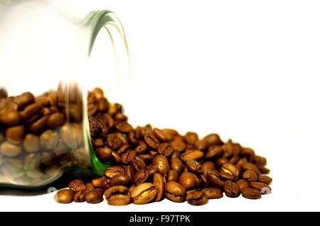 Coffee beans spilling from clear glass jar Stock Photo