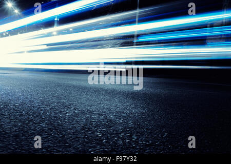 Cars create light blue light trails from their headlights as they move in a city during nightime Stock Photo