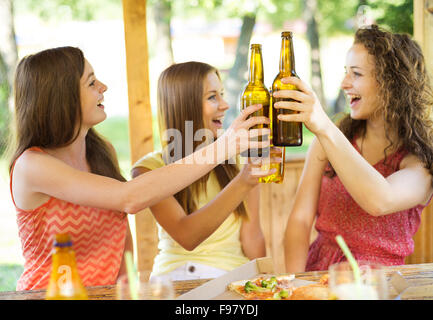 Three happy friends drinking beer, chatting and having fun in pub garden Stock Photo