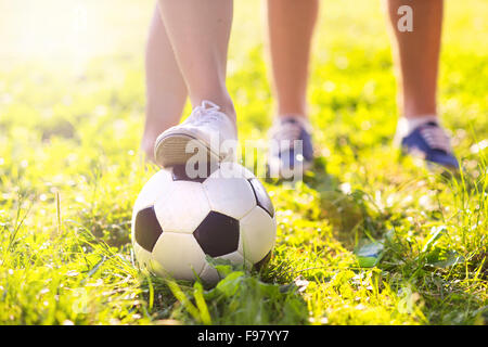 close up of feet and football ball on green grass lawn Stock Photo